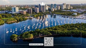 A marina with numerous sailboats docked, surrounded by lush greenery and a cityscape in the background. - Panoramic Views Residence with Private Balcony (Miami)
