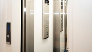 Elevatorinteriør med kontrolpanel, knapper og digital skærm.