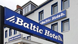 En hotelindgang med et skilt der viser "Baltic Hotel" og et indgangsskilt der angiver "Indgang".