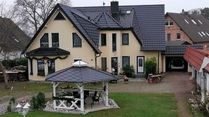 Uma casa de dois andares com varanda coberta, garagem e gramado bem cuidado.