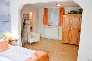 Une chambre à coucher comprenant un lit, une chaise, une armoire, un radiateur et une fenêtre avec des rideaux.
