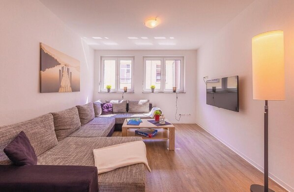 Un salon moderne avec un canapé, une table basse et un téléviseur fixé au mur.