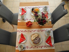 Uma mesa de jantar com toalha florida, pratos com comida e uma tigela de morangos.