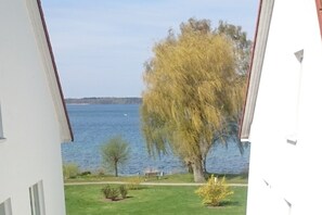 Une vue sur un lac, prise depuis un bâtiment à l’extérieur blanc.