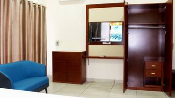 Una habitación con un sofá azul, un armario de madera con espejo y un televisor en la pared.