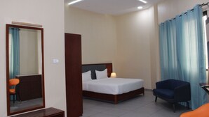 A hotel room with a bed, a chair, a desk, and a mirror. - Ixoras Hotel (Kinshasa)