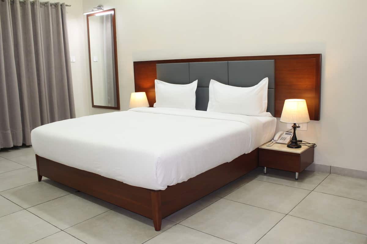 A large bed with a wooden headboard, two bedside tables with lamps, and a mirror on the wall.