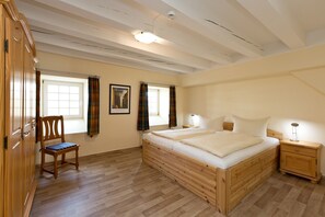 A bedroom with a wooden bed, a nightstand, a chair, and a wardrobe.