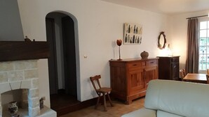 A living room with a fireplace, a wooden cabinet, a white sofa, and a dining area with a table and chairs. - Peace and quiet on a private island in a bucolic setting. (Barro)