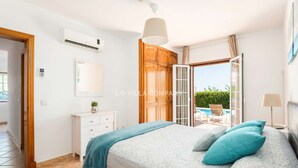 A bedroom with a bed, a wardrobe, a bedside table, a mirror, and an air conditioning unit. - Wonderful Villa Bellavista with Sea Views & Private Pool, Sleeps 8 (Arenal d'en Castell, Es Mercadal)