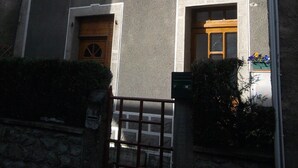 A building with multiple windows, some with shutters, and a number '9' sign above one window. - 8-seater apartment 80 m2 (laruns)