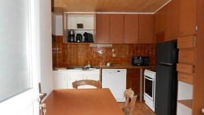 A compact kitchen with wooden cabinets, a black refrigerator, a microwave, and a dishwasher. - 8-seater apartment 80 m2 (laruns)