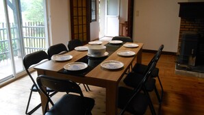 A dining area with a wooden table set for six, surrounded by black chairs. A sliding glass door leads to a balcony with a wooden fence. - 8-seater apartment 80 m2 (laruns)