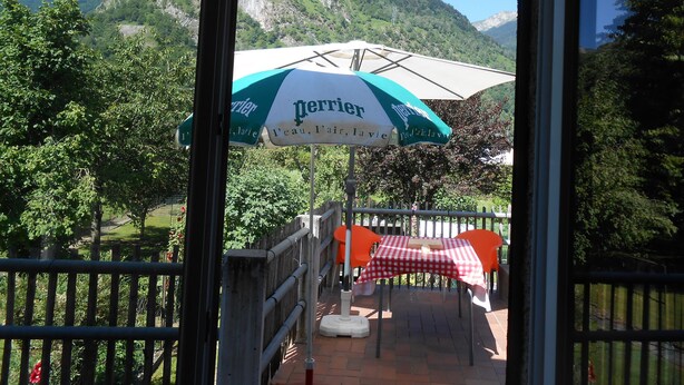 A view of a restaurant with outdoor seating, a mountain backdrop, and a Perrier branded umbrella. - 8-seater apartment 80 m2 (laruns)