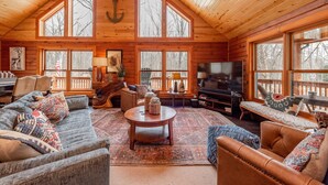 A spacious living room with a high ceiling, large windows, and a fireplace. - Lake Cabin Luxury Near Deep Creek w/ Fire Pit (Swanton)