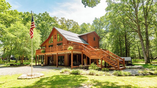 A wooden cabin with a porch, a staircase, and a flagpole. - Lake Cabin Luxury Near Deep Creek w/ Fire Pit (Swanton)
