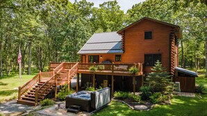 A log cabin with a deck, hot tub, and a flag. - Lake Cabin Luxury Near Deep Creek w/ Fire Pit (Swanton)