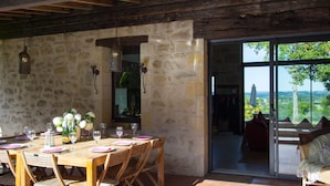 A dining area with a stone wall, wooden ceiling, and a table set for six with chairs.