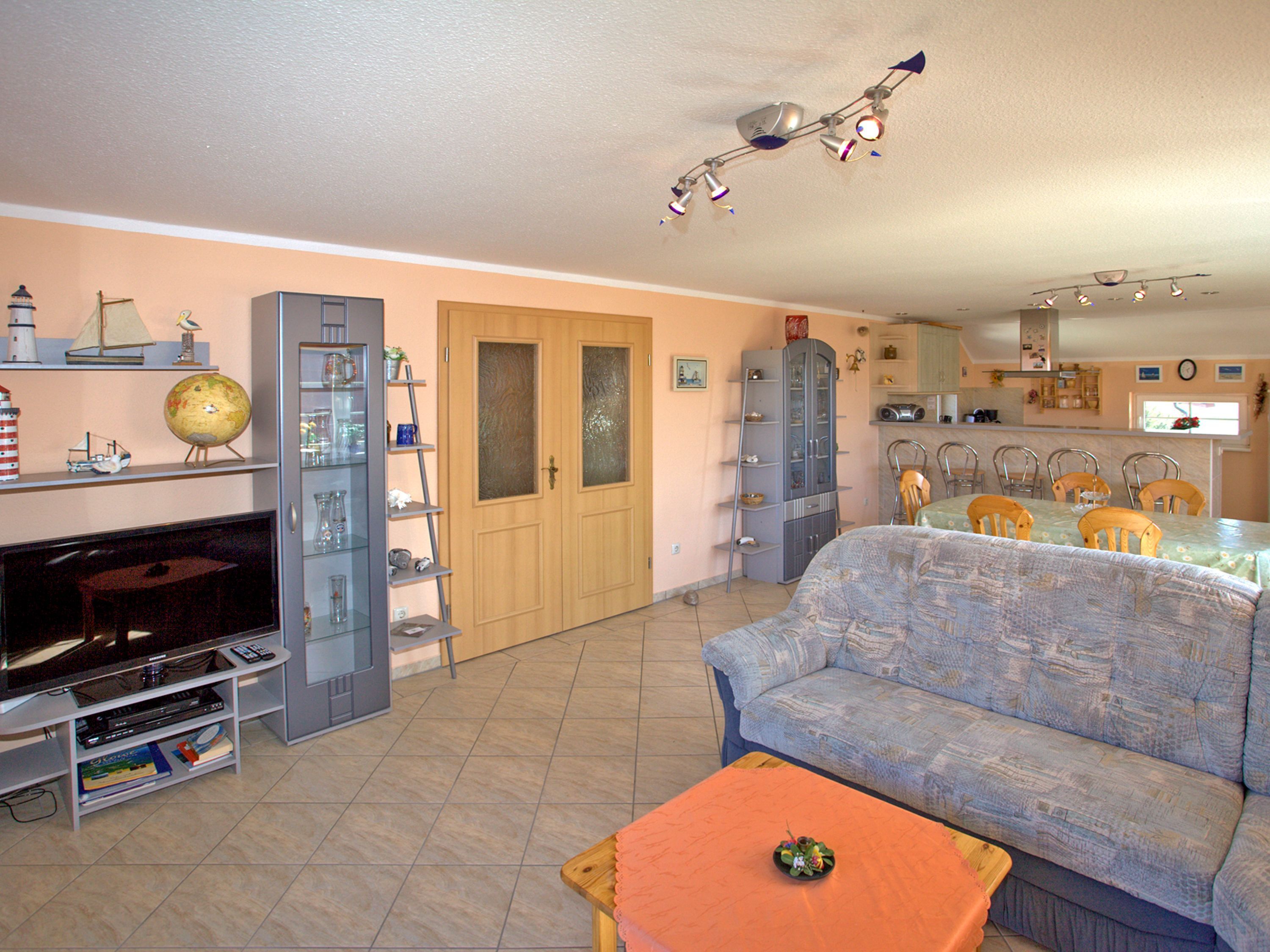 A living room with a sofa, a TV, and a dining area with chairs and a table.
