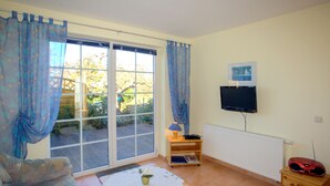 Sala de estar com sofá, mesa de centro, televisão e um pequeno armário de madeira.