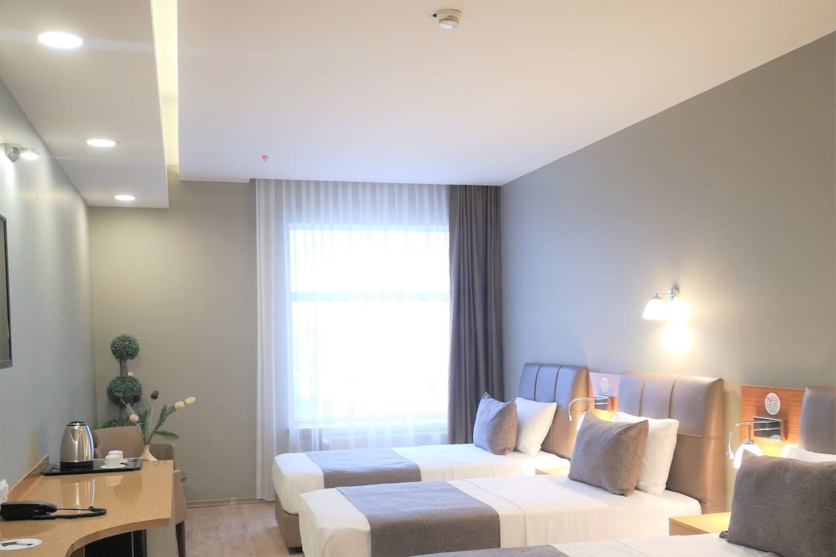 A hotel room with two beds, a desk, a chair, and a window with curtains.