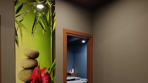 Corredor com um mural de bambu e pedras, que leva a um quarto com cama e mesa de cabeceira.