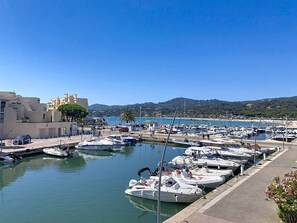 A marina with boats docked, a clear sky, and a hilly landscape in the background.