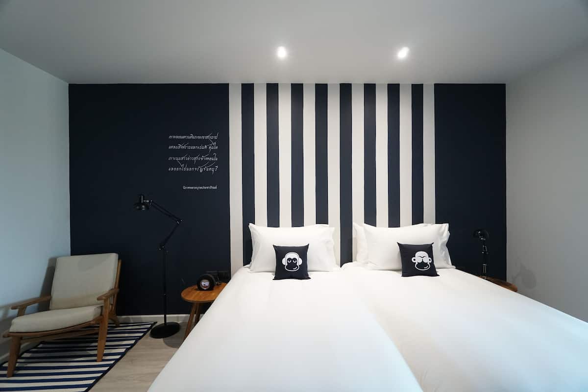 Ein Schlafzimmer mit einem Bett, zwei Kissen, einem Stuhl, einem Schreibtisch und einer Lampe.