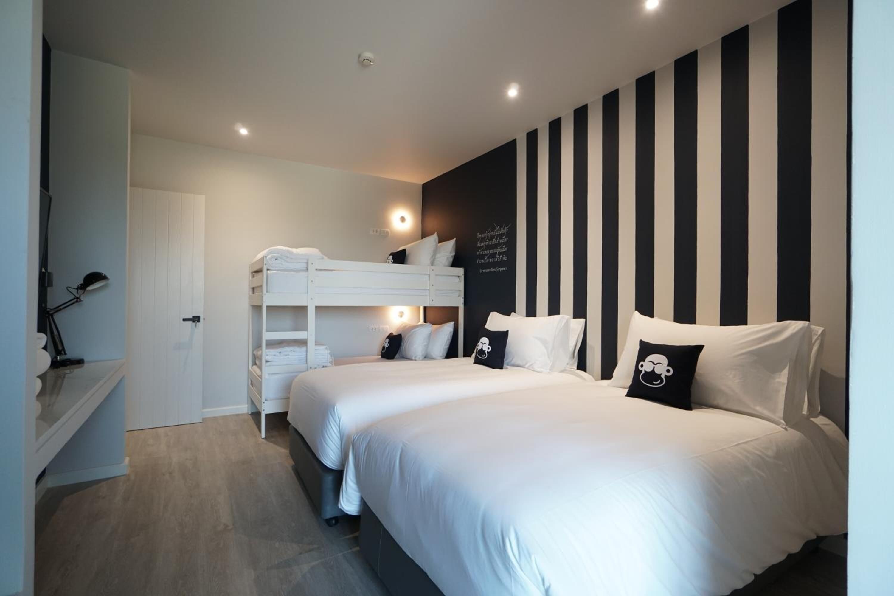 Un dormitorio con dos camas, un armario blanco y una pared a rayas negras y blancas.