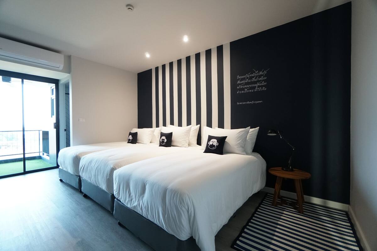 Ein modernes Schlafzimmer mit einem großen Bett, einem kleinen Nachttisch und Blick auf einen Balkon.