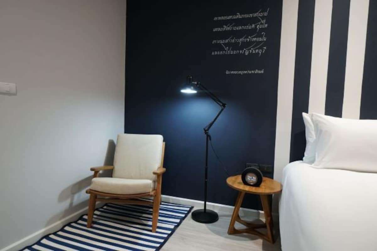 Ein Schlafzimmer mit Bett, Stuhl, Schreibtisch mit Lampe und einer Wand mit Schrift.