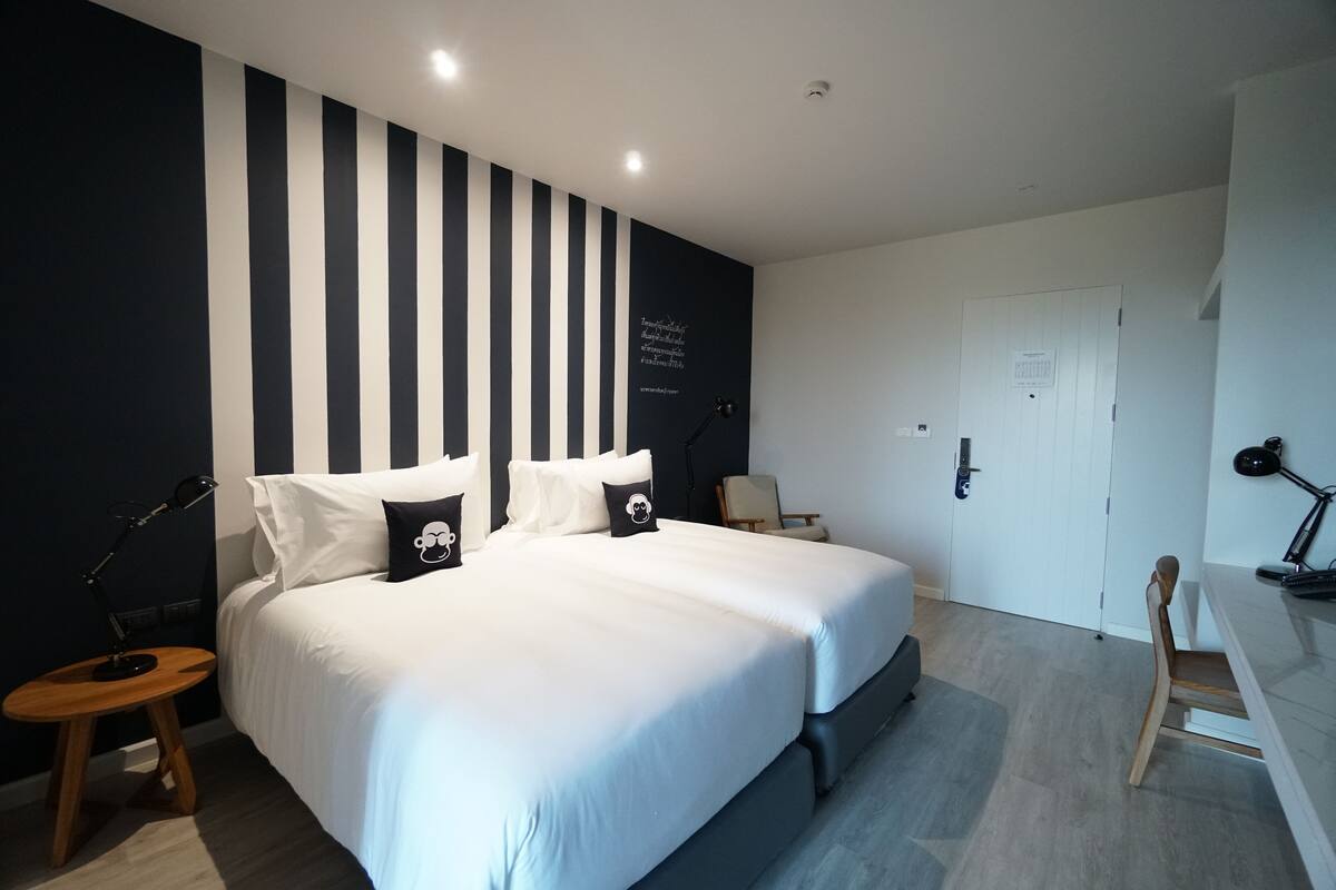 Ein modernes Hotelzimmer mit einem großen Bett, zwei Nachttischen, einem Schreibtisch und einem Sessel.