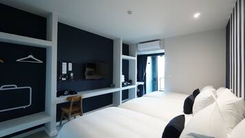 Een moderne hotelkamer met twee tweepersoonsbedden, een bureau met stoel, een televisie en een kledingkast.