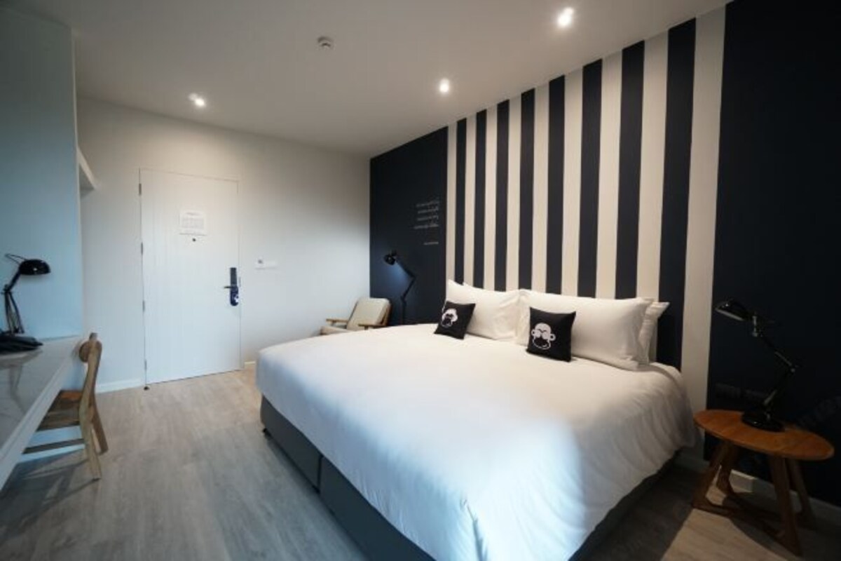 A modern bedroom with a large bed, a desk, and a chair.