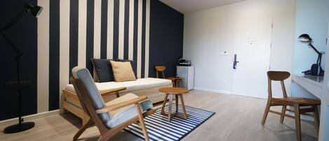A modern living room with a sofa, two wooden chairs, a coffee table, and a striped rug.