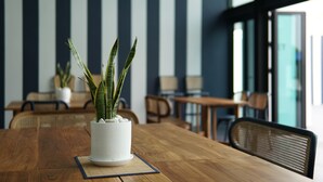 Una mesa de madera con una planta en maceta, pared a rayas y muebles modernos en una habitación bien iluminada.