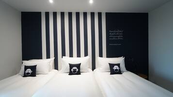 A modern bedroom with a large bed, black and white striped wall, and decorative pillows.