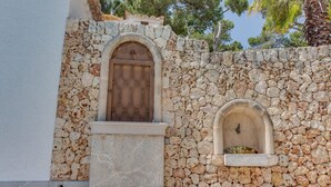 A stone wall with a wooden door and a small window. - Ram de Mar - Villa in Cala Ratjada for 10 people with sea views (Capdepera)