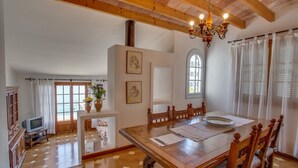 A dining area with a wooden table and chairs, a chandelier, and a view of the sea through a window. - Ram de Mar - Villa in Cala Ratjada for 10 people with sea views (Capdepera)