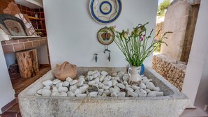 A stone sink with pebbles, a clay pot, and a vase with flowers. - Ram de Mar - Villa in Cala Ratjada for 10 people with sea views (Capdepera)