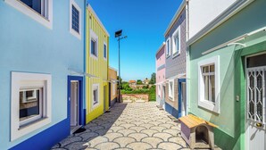 Une rue étroite bordée de bâtiments aux couleurs vives, un ciel dégagé et un trottoir pavé.