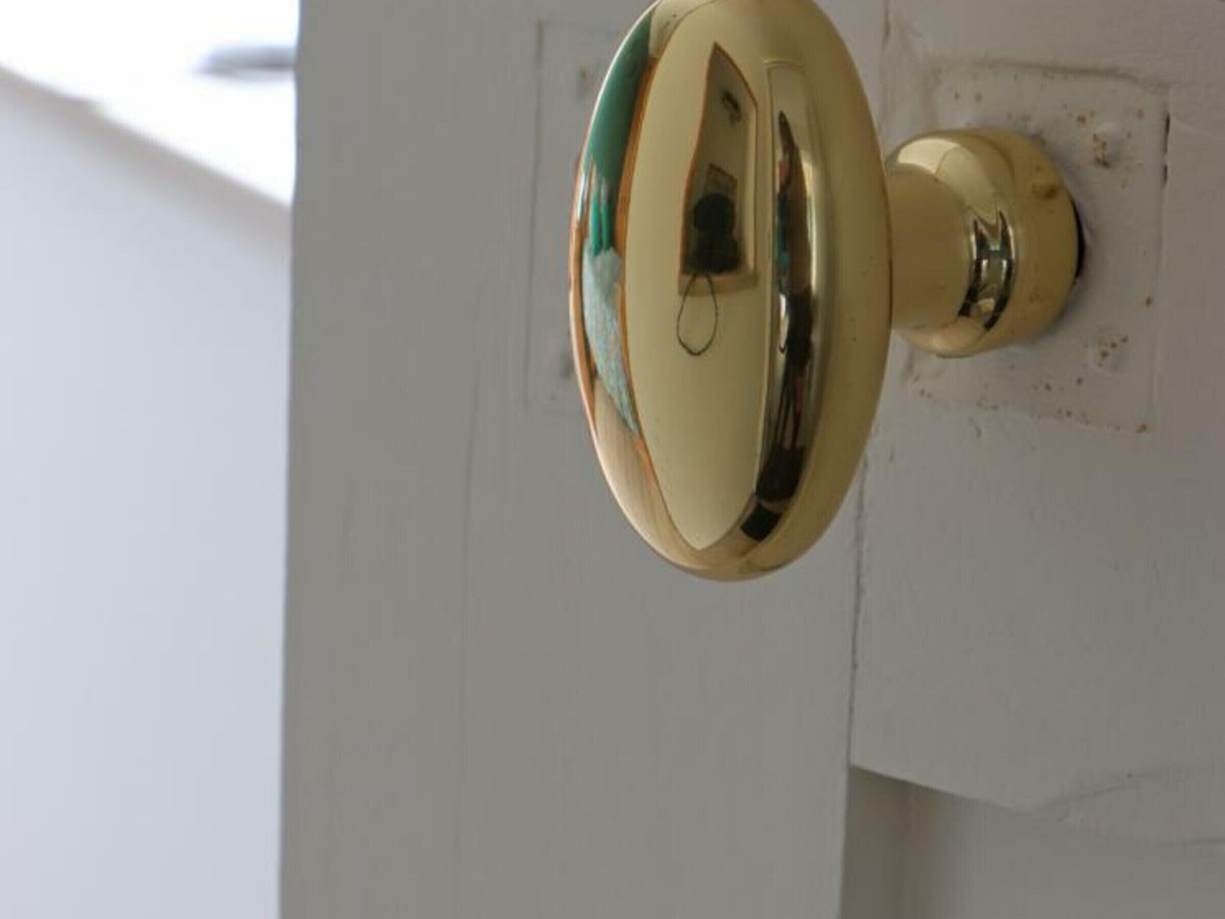Uma maçaneta dourada em uma porta branca.