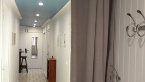 Un couloir avec un sol à motifs, un banc en bois et un miroir accroché au mur.