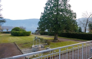 Une cour agrémentée d’un grand arbre, d’une pelouse bien entretenue et d’un puits en pierre.
