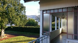 Une véranda couverte offrant une vue sur un lac et des montagnes.