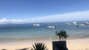A beach with several boats in the water and a clear sky.