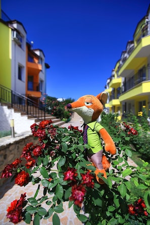 A plush toy in a garden setting with buildings in the background. - Luxury 1-Bedroom Apartment in MiniSmart Complex RainbowGarden (Balchik)