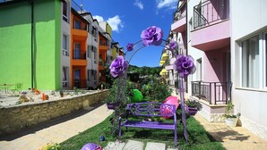Une cour avec un banc violet, des plantes en pot et une petite sculpture de tortue.