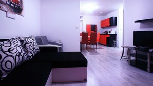 Un salon moderne avec un canapé, un pouf et un coin repas doté de chaises rouges.