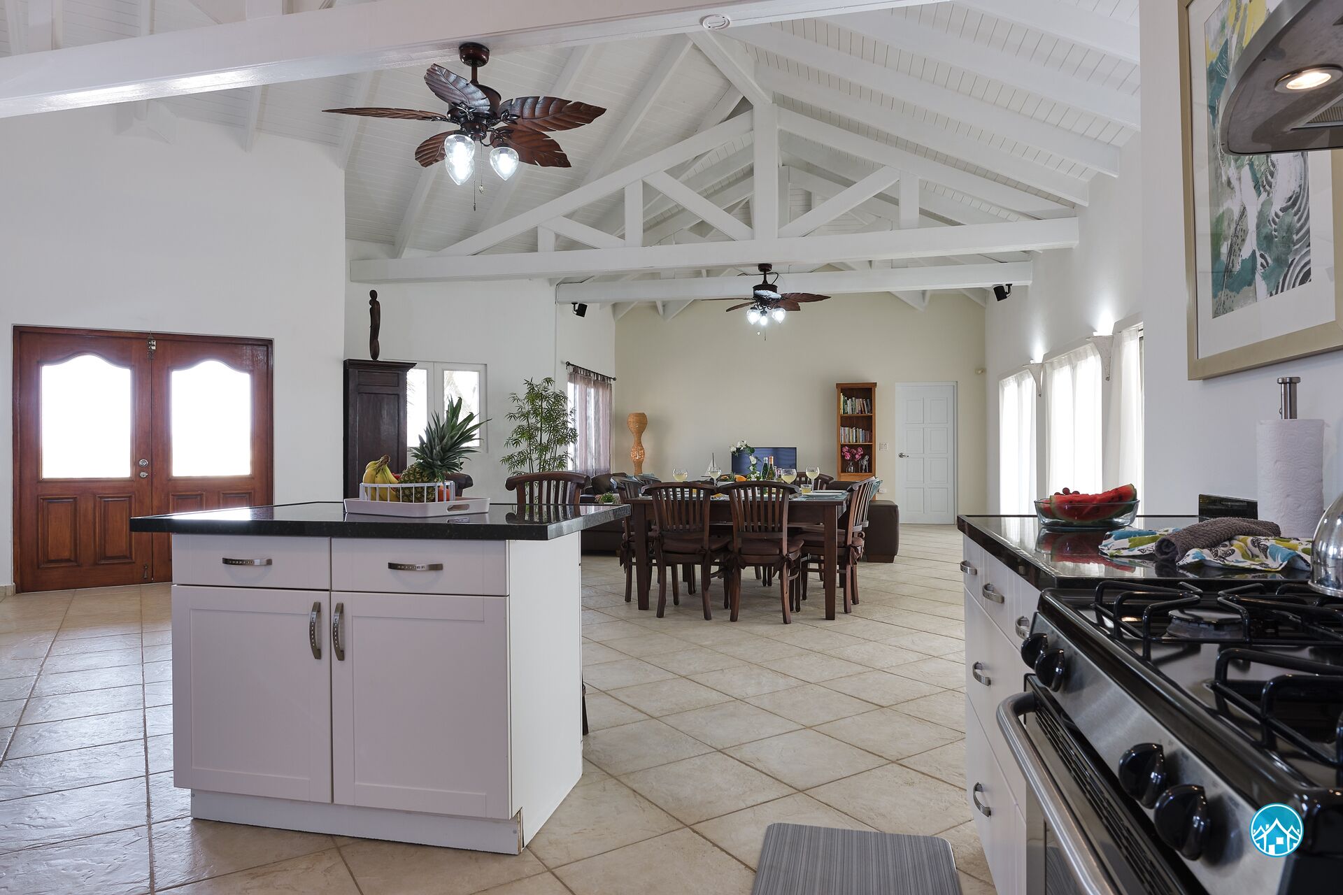 Una cocina amplia con una isla central, zona de comedor y ventilador de techo.